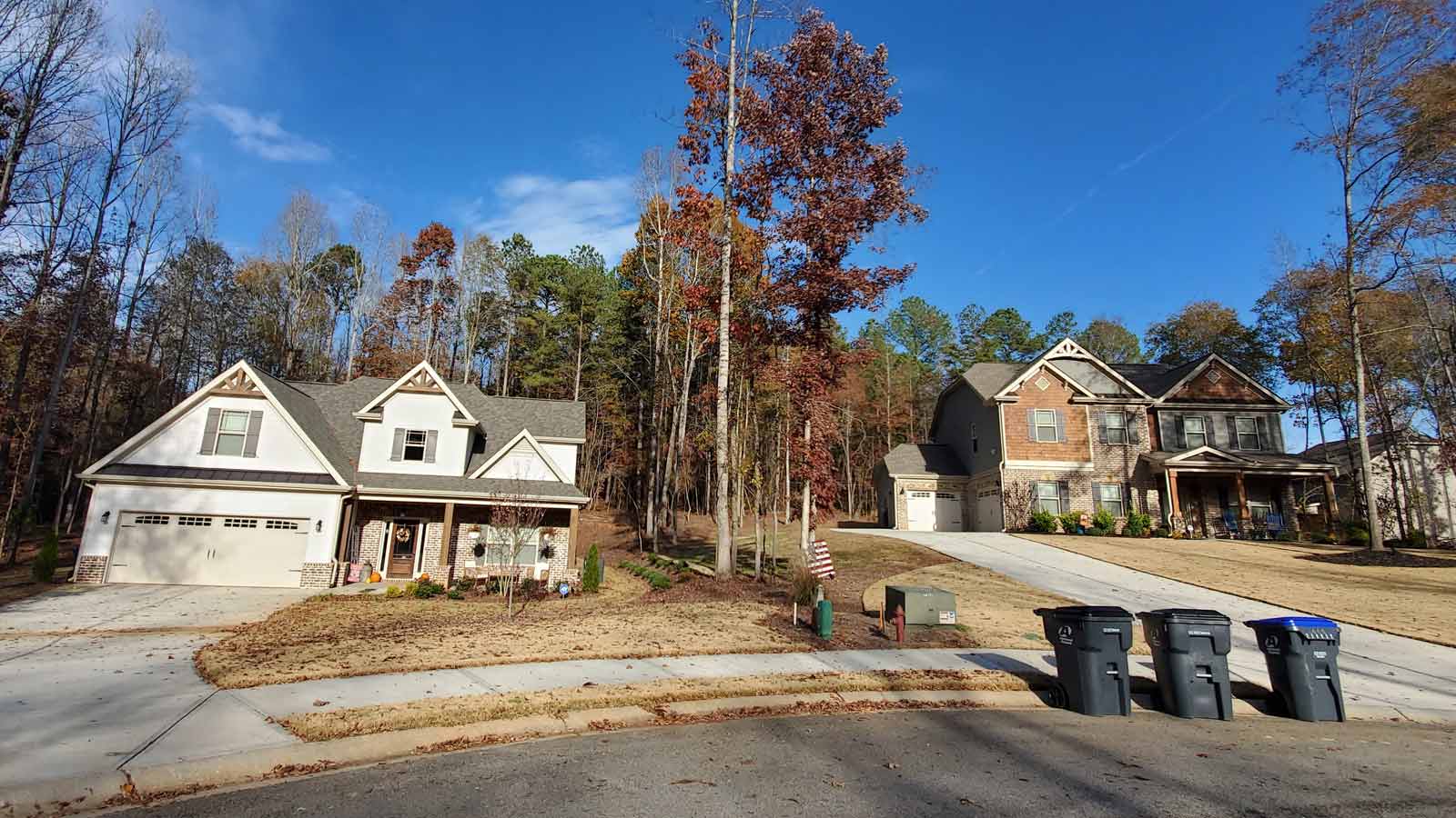 2 large homes in subdivision with garbage cans sitting out by driveway